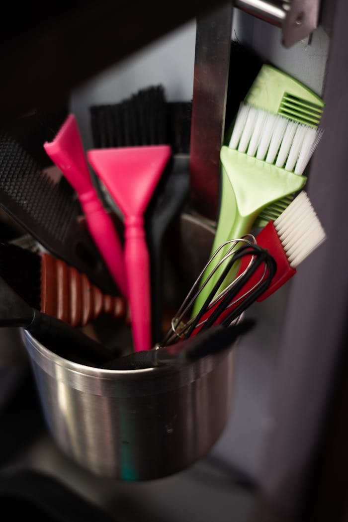 Vibrant brushes and tools in a metal pot at a salon vividly captured.