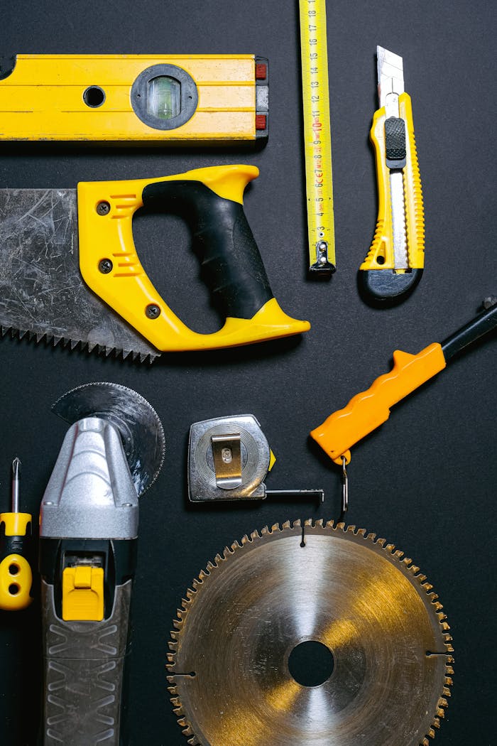services-04 A collection of yellow and black construction tools arranged on a dark flat surface, ideal for DIY projects.