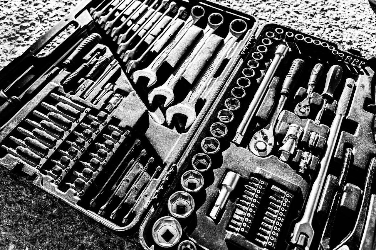 who-we-are Close-up black and white photo of a complete wrench and socket tool set within a toolbox.